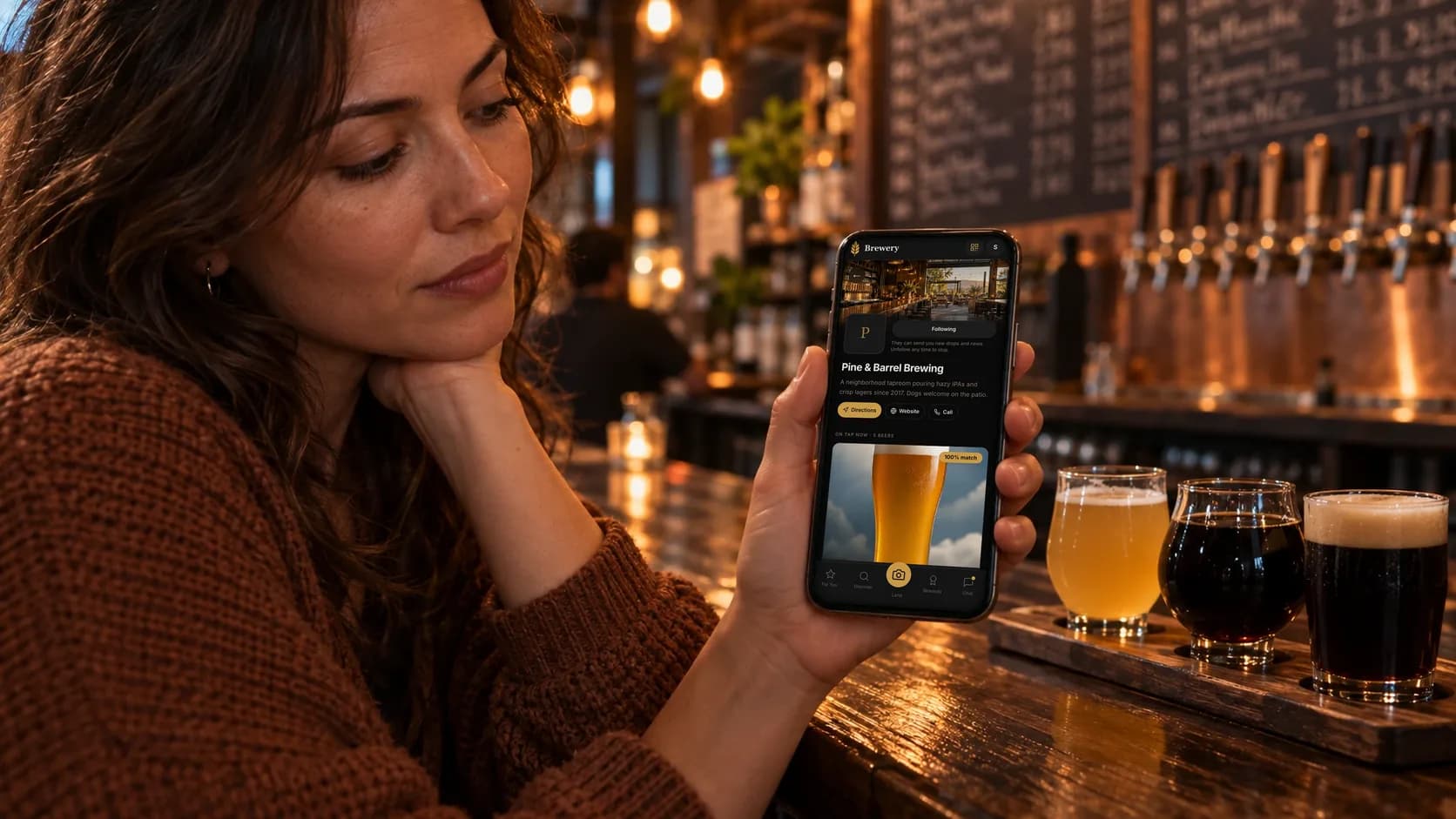 A drinker at the bar looks at the Pine & Barrel Brewing page in the Barley app, with what is on tap now, next to a flight of three beers.