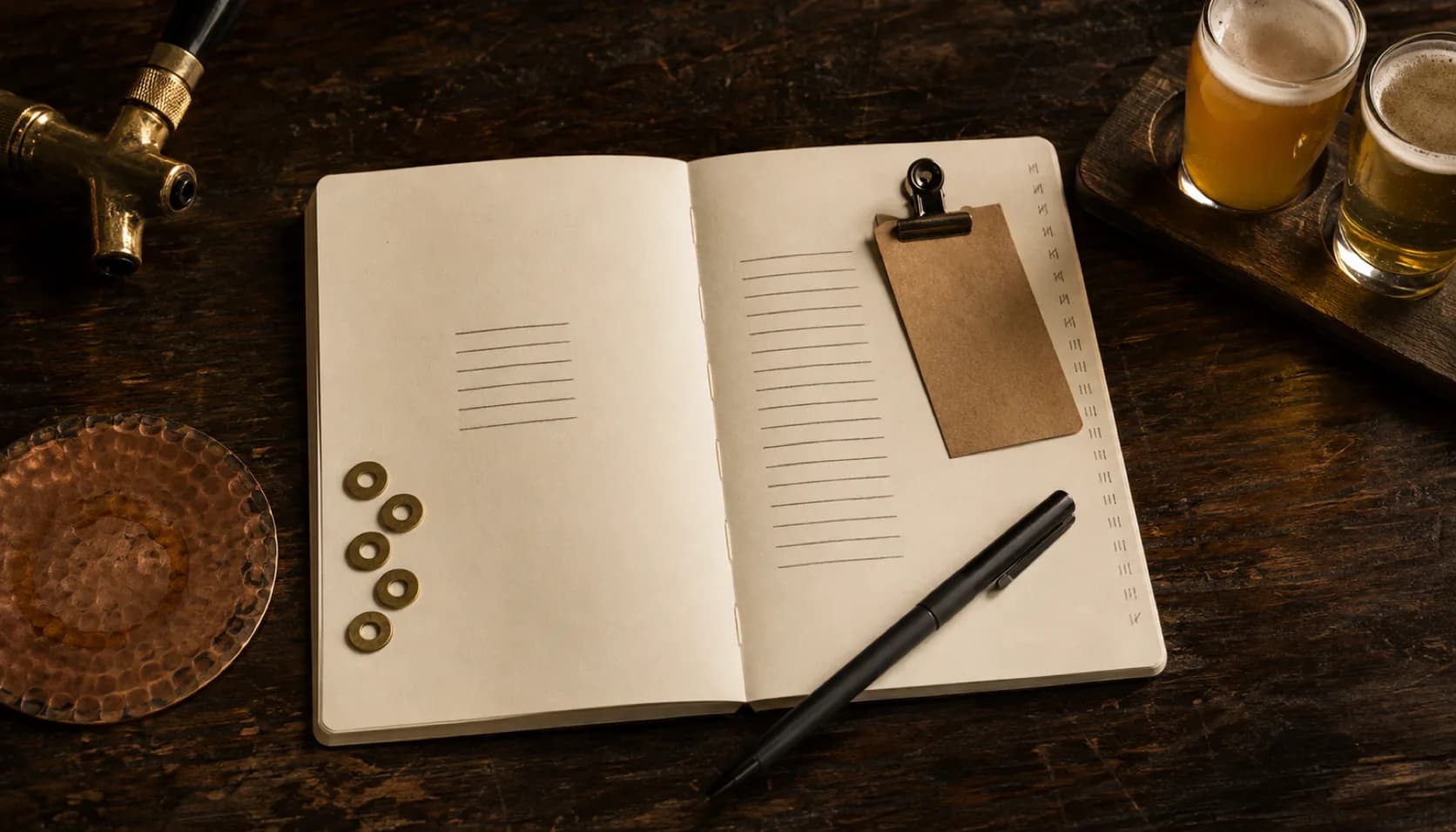 An open notebook on dark wood photographed from above, two columns of ruled lines standing in for two pricing tiers, with a pen, a copper tray and a brass tap handle around the edge of the frame.